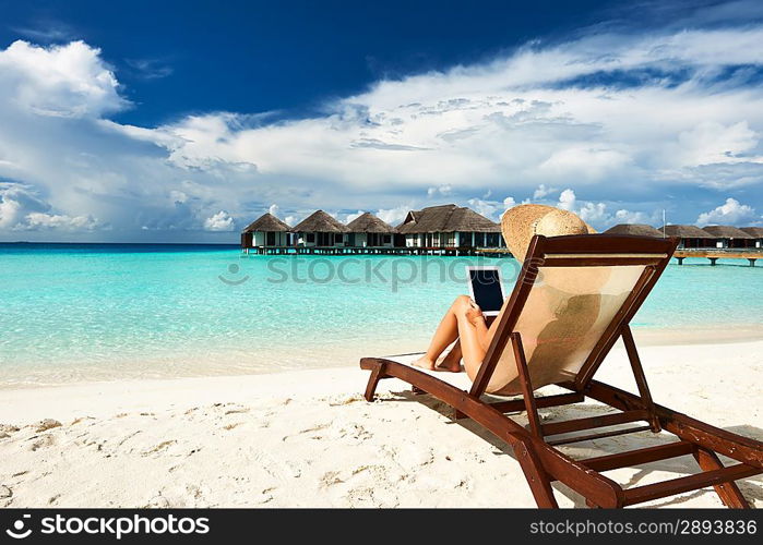 Young woman in hat with tablet pc at the beach