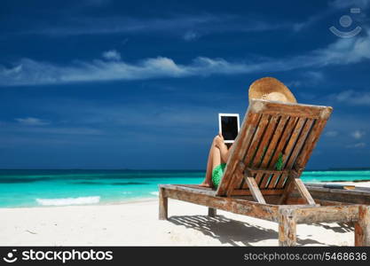 Young woman in hat with tablet pc at the beach