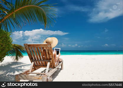 Young woman in hat with tablet pc at the beach