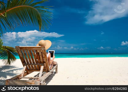 Young woman in hat with tablet pc at the beach