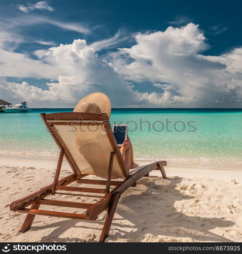 Young woman in hat with tablet pc at the beach. Young woman with tablet pc at the beach