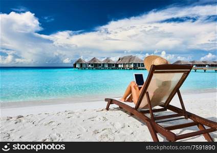 Young woman in hat with tablet pc at the beach