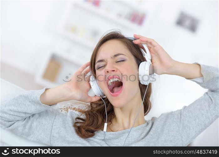 young woman in headphones while singing at home