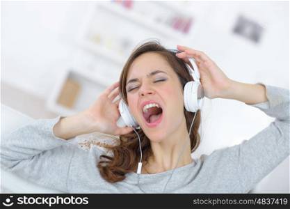 young woman in headphones while singing at home