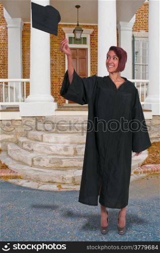 Young woman in her graduation robes throwing her cap