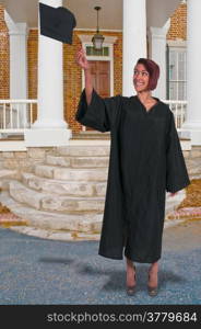 Young woman in her graduation robes throwing her cap