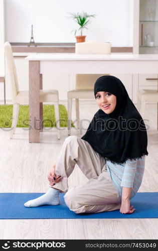Young woman in hijab doing exercises at home 