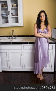 Young woman in kitchen, arms crossed