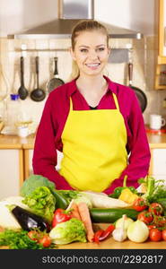 Young woman in kitchen having many vegetables about to cook something healthy and vegetarian. Woman in kitchen having many vegetables