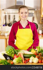 Young woman in kitchen having many vegetables about to cook something healthy and vegetarian. Woman in kitchen having many vegetables