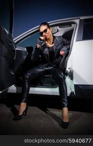 Young woman in leather clotes with car
