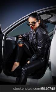 Young woman in leather clotes with car