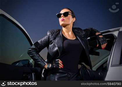 Young woman in leather clothes with car