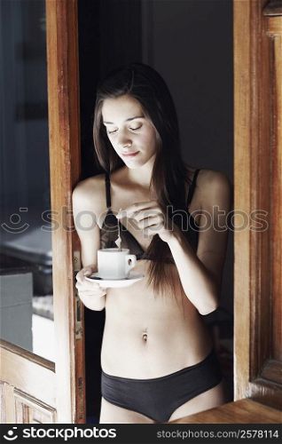 Young woman in lingerie dipping a tea bag in a cup of tea