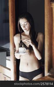 Young woman in lingerie dipping a tea bag in a cup of tea