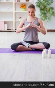 Young woman in lotus pose meditating in spa gym