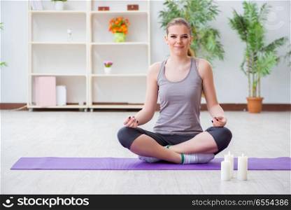 Young woman in lotus pose meditating in spa gym