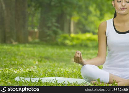 Young woman in lotus position meditating in a park