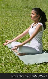 Young woman in lotus position meditating in a park