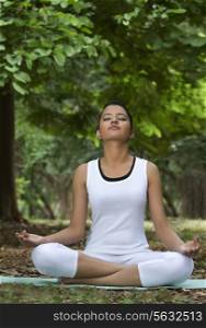 Young woman in lotus position meditating in a park