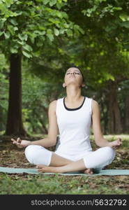 Young woman in lotus position meditating in a park