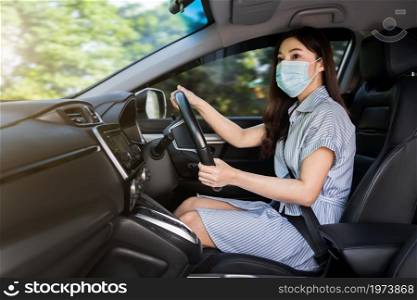 young woman in medical mask driving a car. for protect covid-19 (coronavirus) pandemic