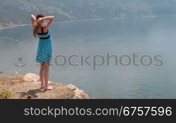 Young woman in mini dress on rock by the sea