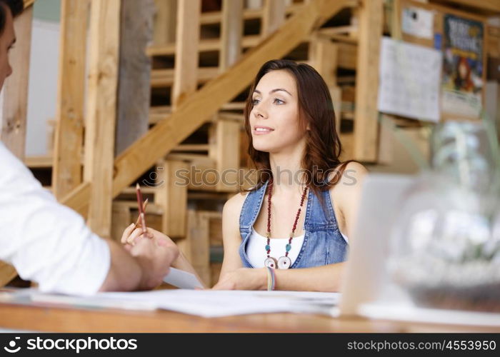 Young woman in office talking to her colleague. Smiling young designer in office talking to her colleague