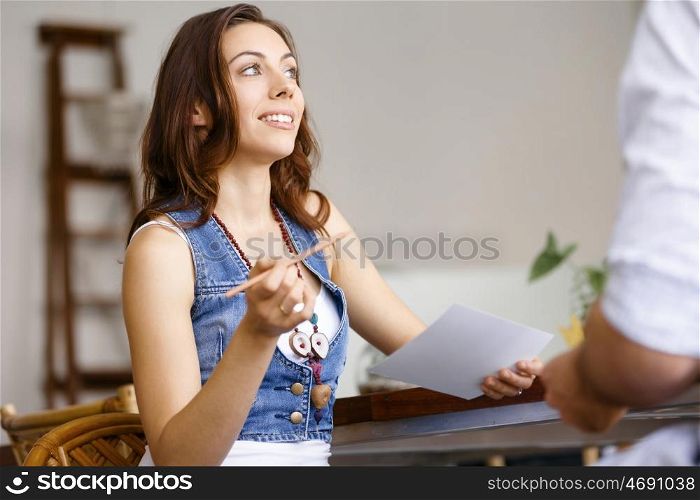 Young woman in office talking to her colleague. Smiling young designer in office talking to her colleague