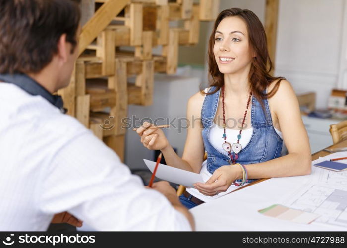 Young woman in office talking to her colleague. Smiling young designer in office talking to her colleague