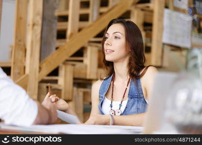 Young woman in office talking to her colleague. Smiling young designer in office talking to her colleague