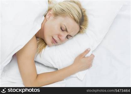 Young woman in pain lying on bed