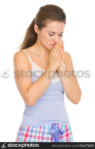 Young woman in pajamas praying before sleep
