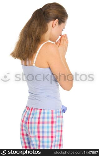 Young woman in pajamas praying before sleep. Rear view