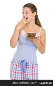 Young woman in pajamas with cup of coffee yawing after sleep