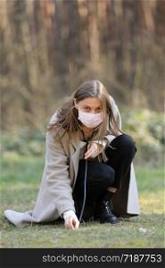 young woman in protective mask listening to the ground with stethoscope in the park. selective focus. copy space.. young woman in protective mask listening to the ground with stethoscope in the park. selective focus. copy space