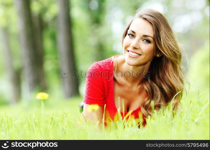 young woman in red dress lying on grass. beautiful young woman in red dress lying on grass