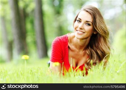 young woman in red dress lying on grass. beautiful young woman in red dress lying on grass