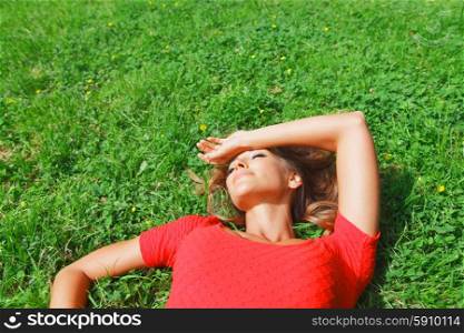 young woman in red dress lying on grass. beautiful young woman in red dress lying on grass