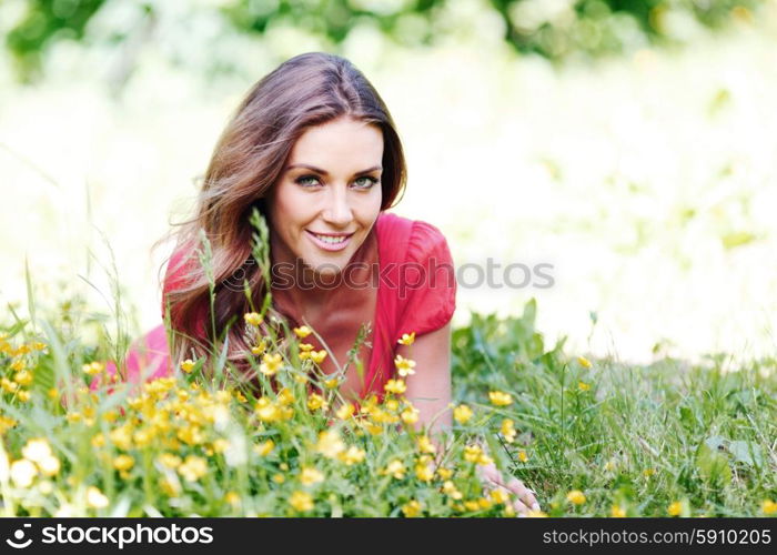 young woman in red dress lying on grass. beautiful young woman in red dress lying on grass