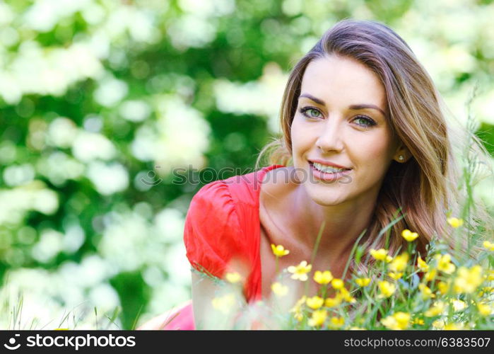 young woman in red dress lying on grass. beautiful young woman in red dress lying on grass