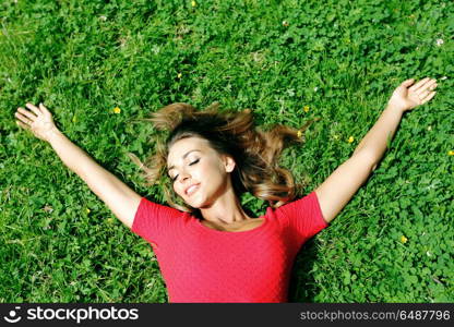 young woman in red dress lying on grass. beautiful young woman in red dress lying on grass