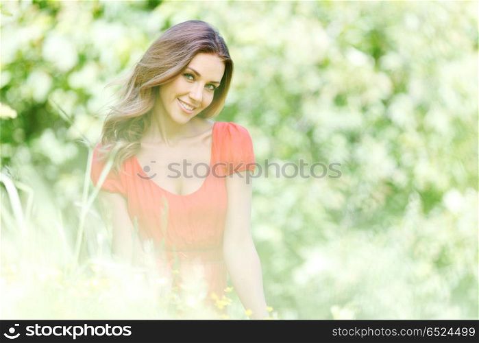 young woman in red dress sitting on grass. beautiful young woman in red dress sitting on grass