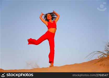 Young woman in red runs on sand