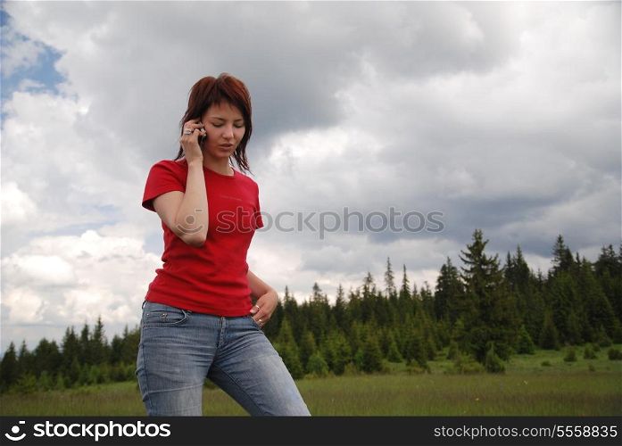 young woman in red talking by cellphone outside
