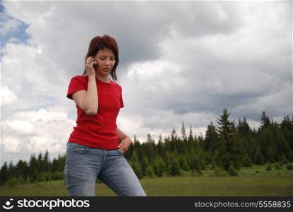 young woman in red talking by cellphone outside