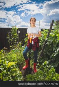 Young woman in rubber boots working at backyard garden