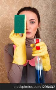 Young woman in rubber gloves with washing sponge and cleaning agent. Housekeeping concept