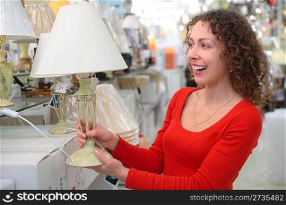 young woman in shop of house technics with table lamp