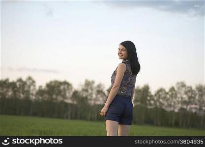 Young woman in shorts walks towards woodland